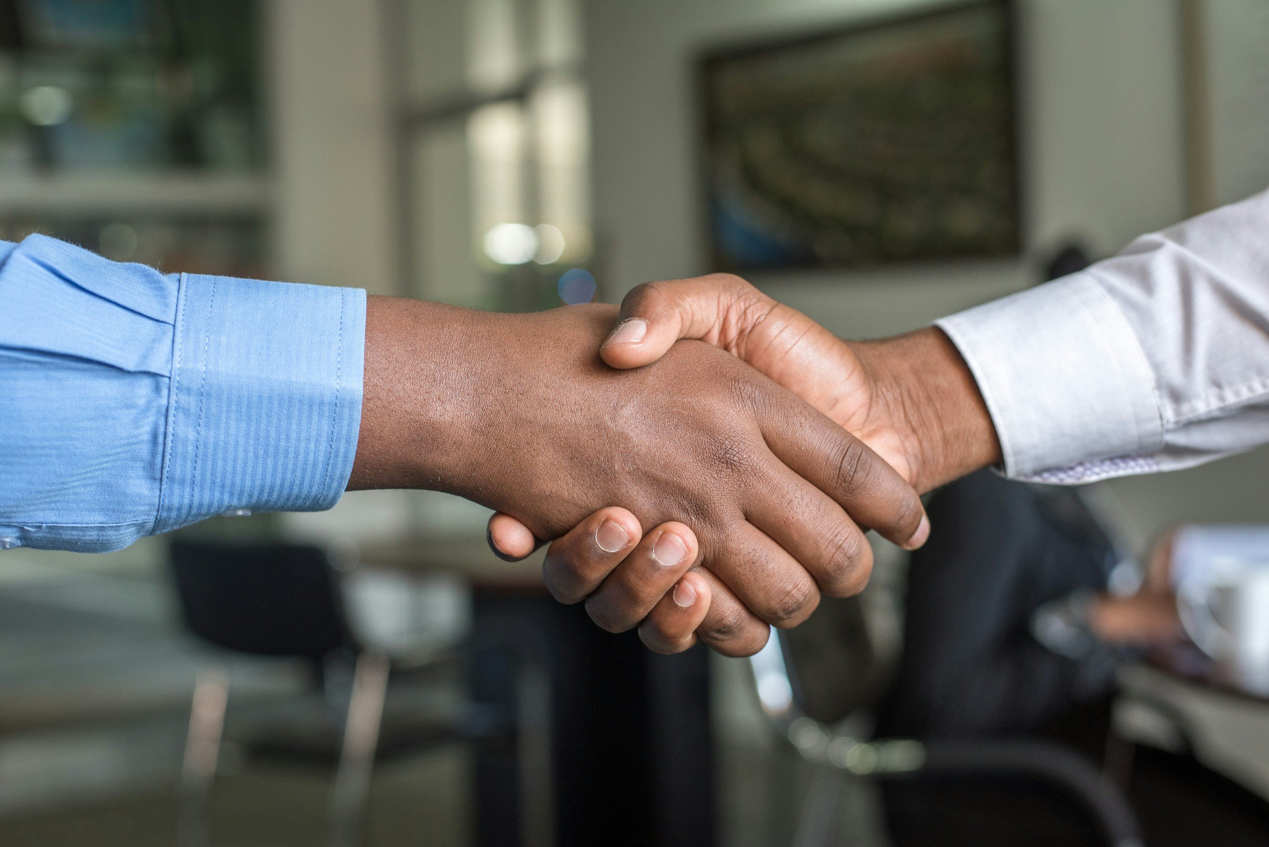 Two people shaking hands in an office setting.